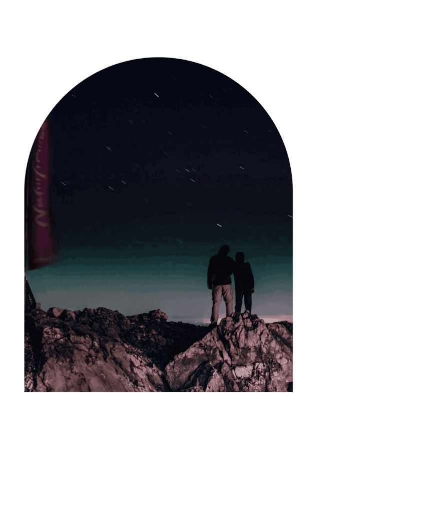 silhouette de deux personnes debout sur des rochers bruns sous la nuit étoilée